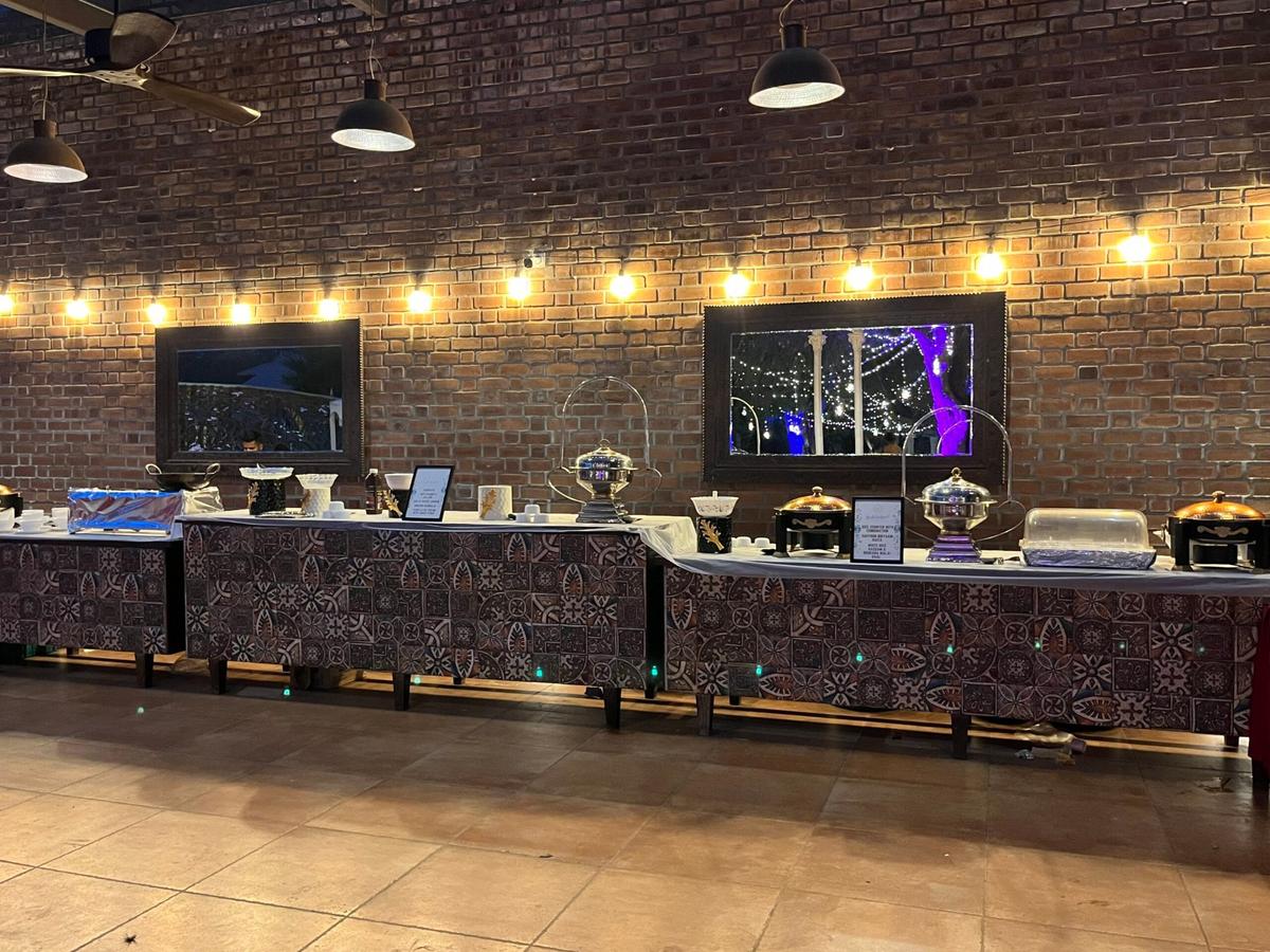 Luxury buffet with silver chafing dishes against rustic brick wall — Sukhdev Caterers Bangalore